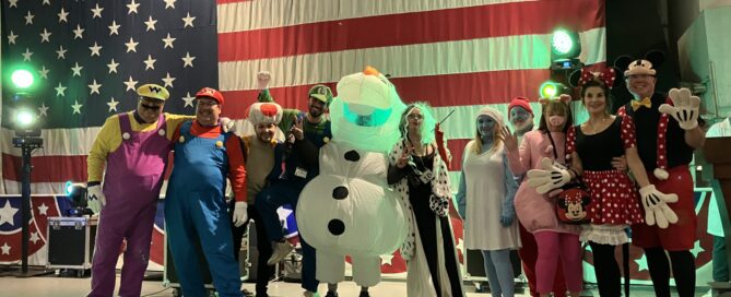 Eleven people wearing Cartoon Character-themed costumes on a stage.