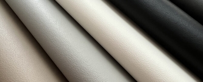 Textured outdoor fabrics in varying shades of gray, white and black, neatly rolled and arranged for display.