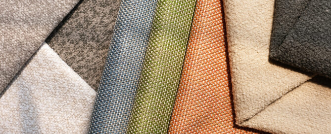 A collection of versatile outdoor fabrics in various colors, including greys, greens, oranges and beiges, layered in an overlapping arrangement.